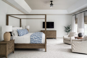 Bedroom with blue and white bedding, canopy bed, dresser with tv above, large table lamps on nightstands