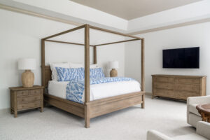 Bedroom with blue and white bedding, canopy bed, dresser with tv above, large table lamps on nightstands
