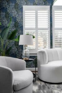 beautiful sunroom with teal walls, botanical wallpaper, modern lighting and furniture