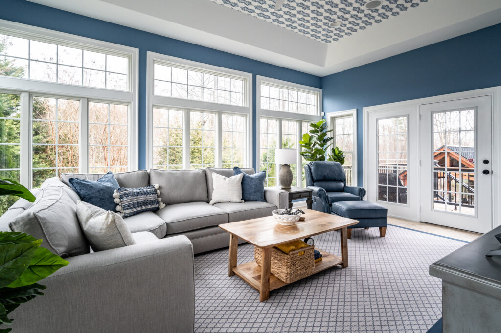 Beautiful blue sunroom with patterned wallpapered tray ceiling and grey sectional