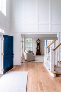 Foyer interior design in Maryland showing a custom millwork, blue door, white oak floors, custom rug.