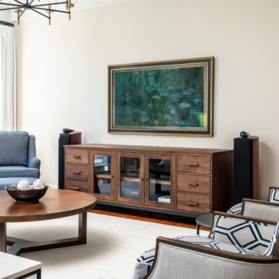 Living room with Samsung Frame TV showcasing artwork, beautiful custom dual fabric chairs, walnut wood furniture.