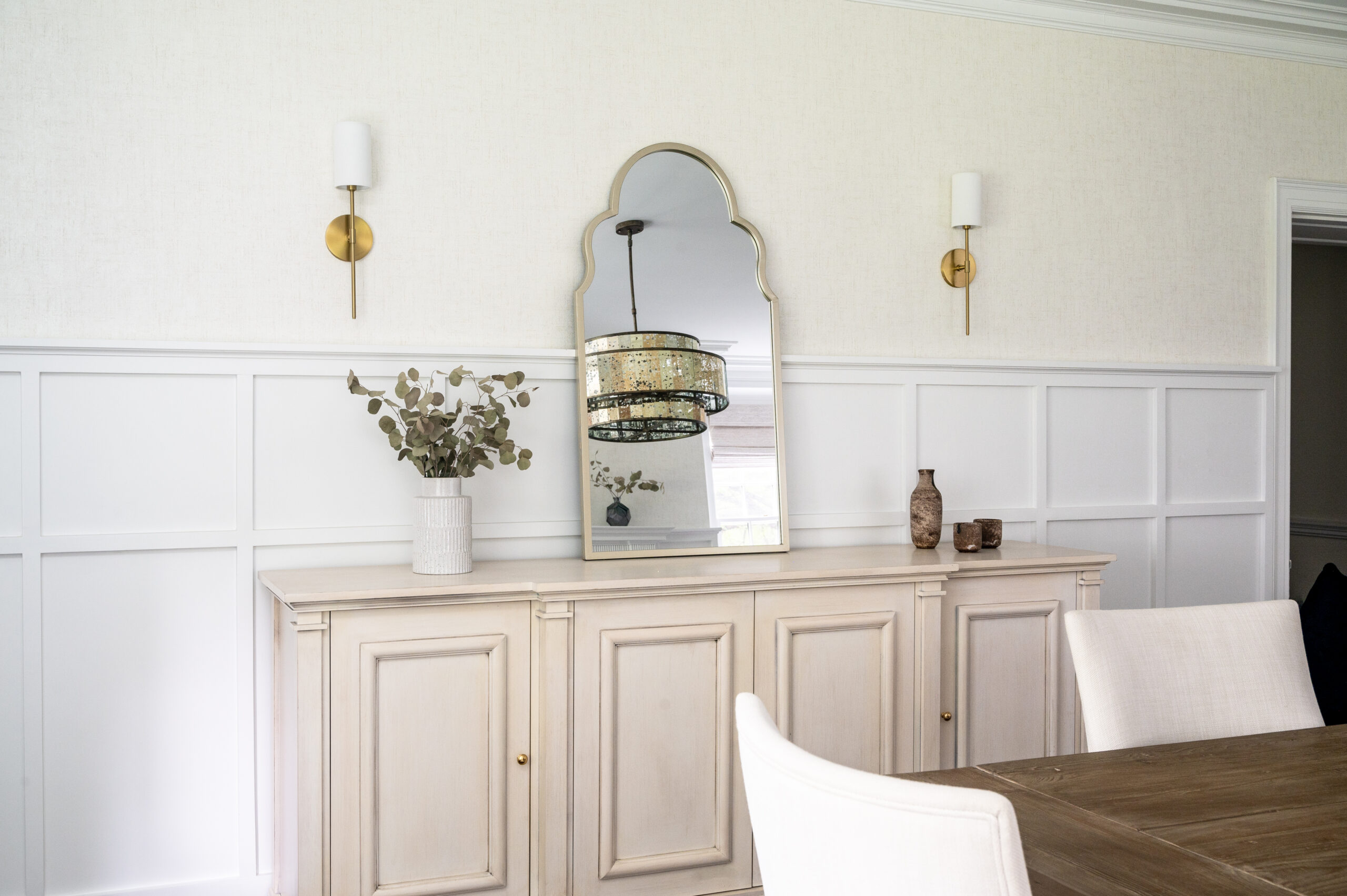 Beautiful console, gold wall scones with white linen shades, and grasscloth wallpaper above custom wainscotting.