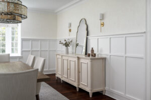 Beautiful buffet in dining room with wainscotting and wall sconces.
