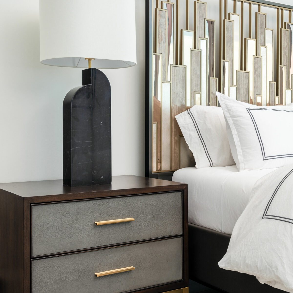 Beautiful mixed metal headboard, marble lighting, faux shagreen nightstand, and luxury linens on the bed.