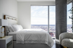 Guest bedroom in Baltimore penthouse with white bedding, marble lamp, swivel chair