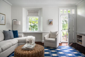 Cozy den space with blue and white rug, chaise sofa, and swivel chair. 