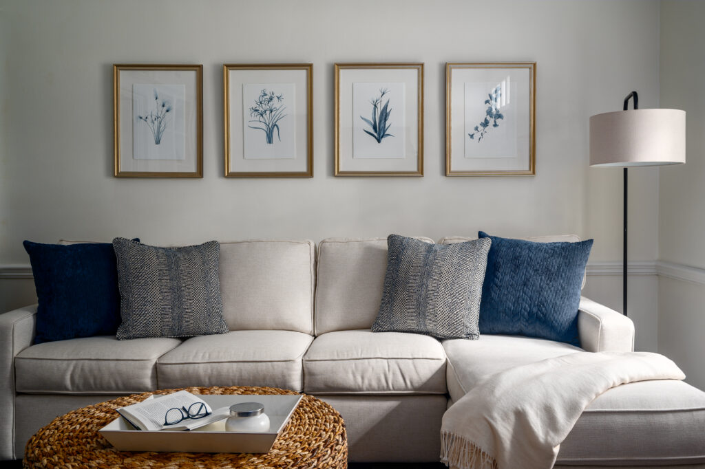 soft lighting spilling into a comfortable room that features a sofa with a collection of 4 pieces of floral art