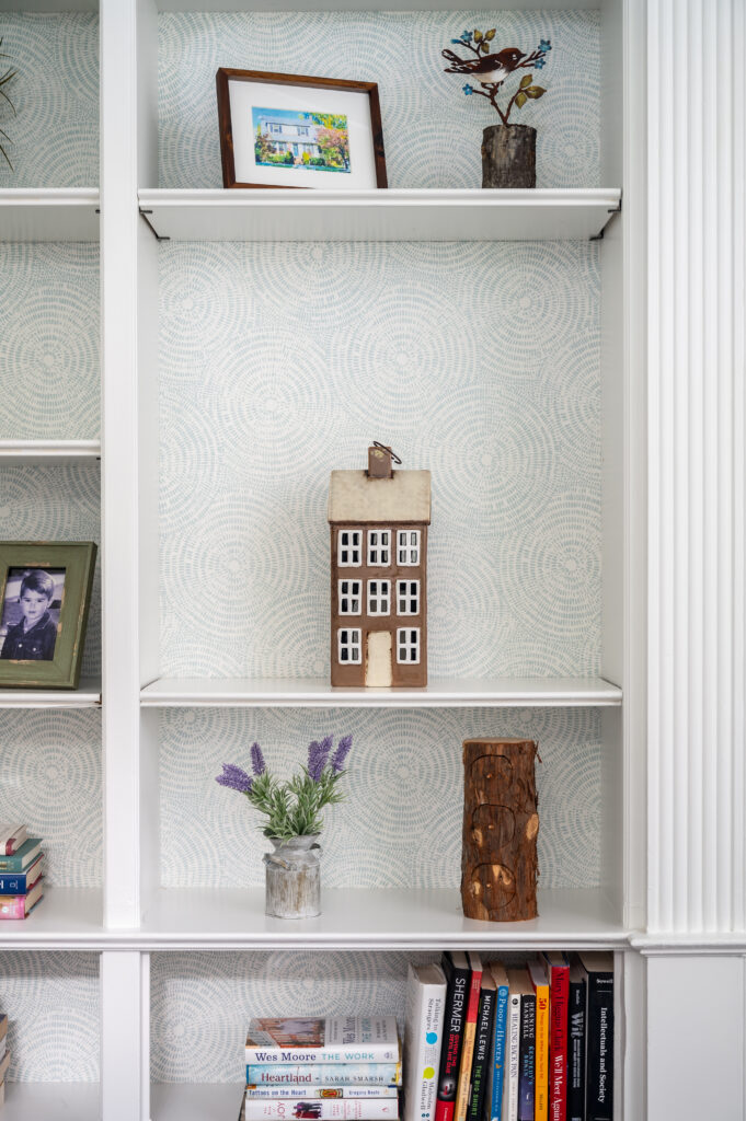 Built-in bookcase with soft wallpaper lining the back wall. 