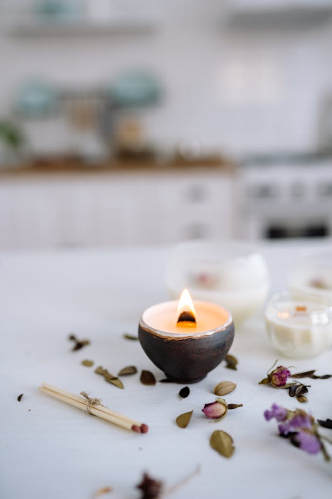 Aesthetic still life of lit candles with dried flowers, creating a serene atmosphere.