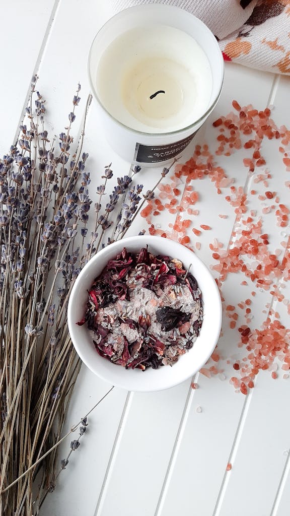 Elegant composition of potpourri, lavender, candle, and Himalayan salt on a white surface.