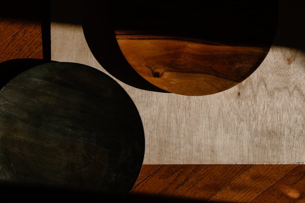 Minimalist wooden kitchenware casting artistic shadows on a rustic surface.