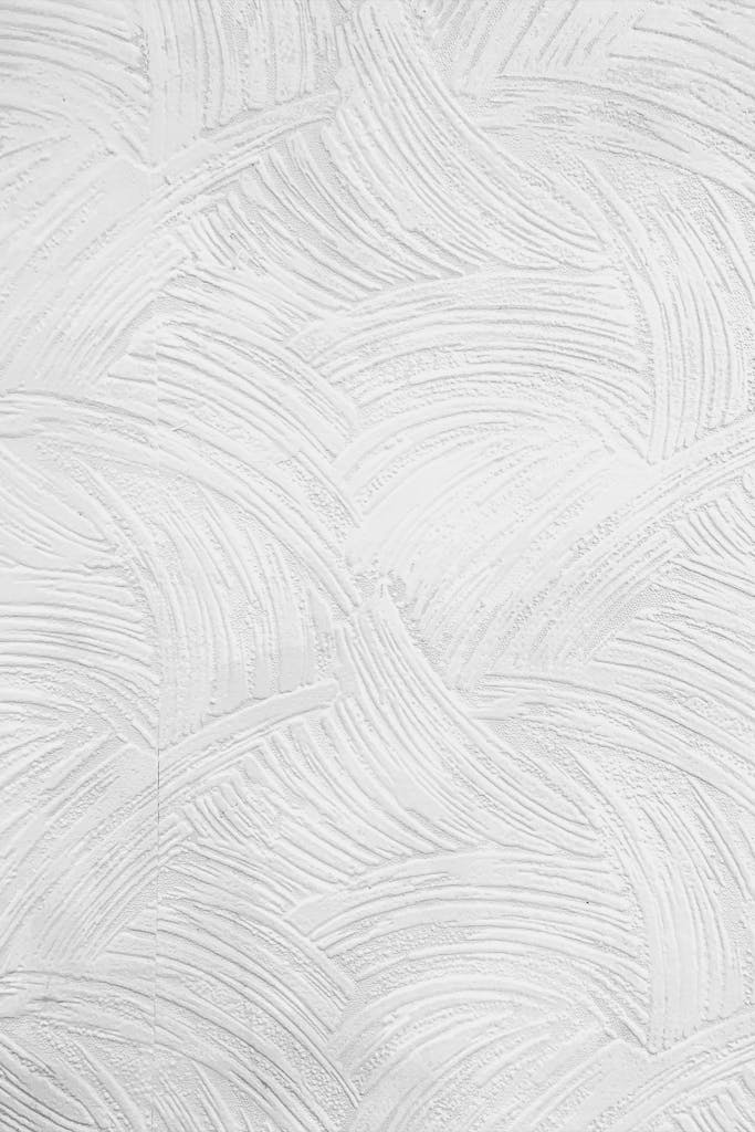 Minimalistic textured white plaster wall ideal for backgrounds and designs.