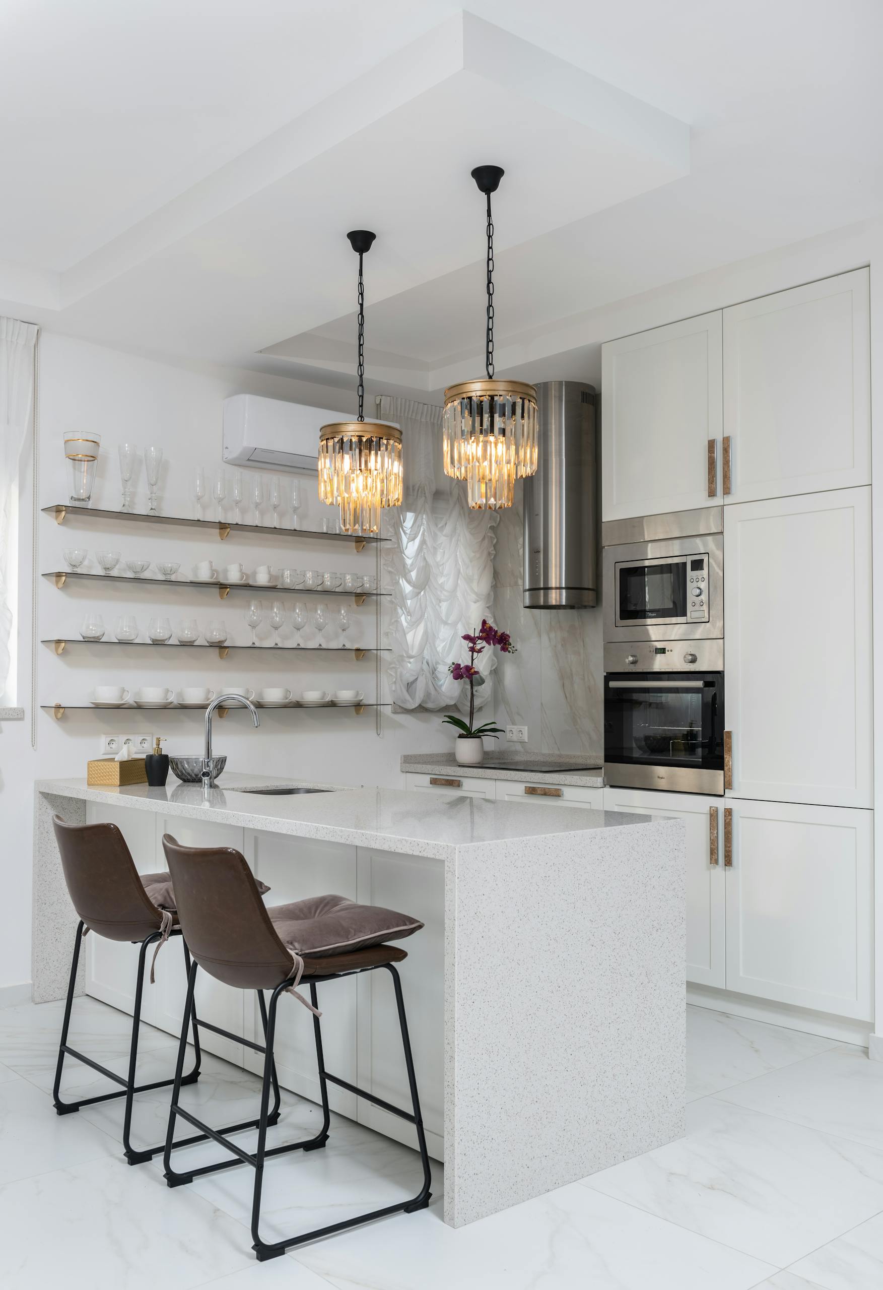 Sleek modern kitchen interior with white cabinets and elegant pendant lights.