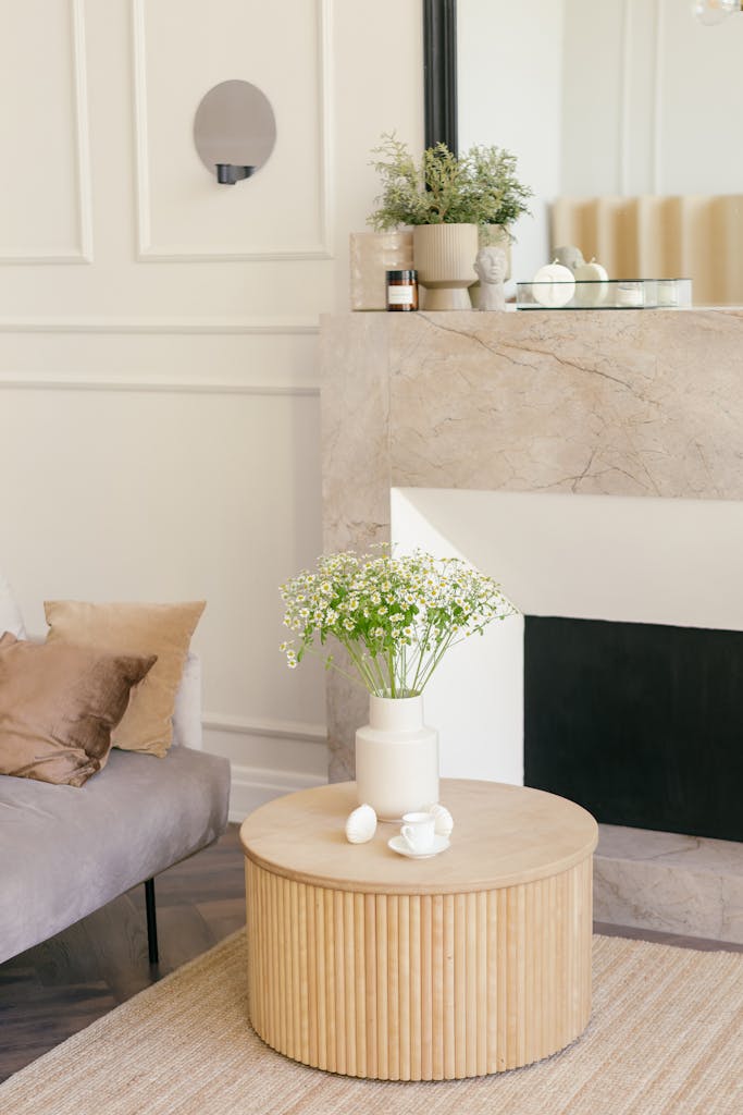 Stylish living room featuring a white vase with flowers on a wooden table beside a cozy sofa.