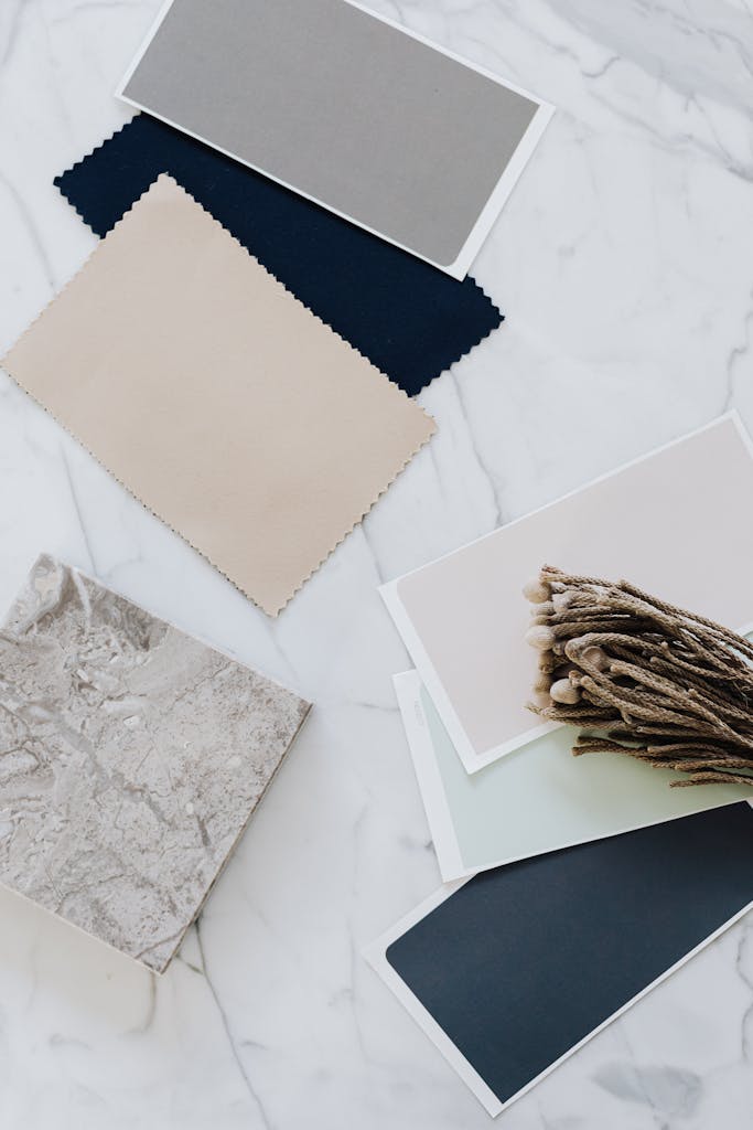 Flat lay of minimalist fabric swatches and twigs on a marble table.