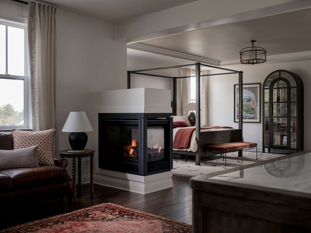 Luxury primary suite designed for a well-traveled couple, featuring a four-poster bed, custom reading lounge, built-in bookcase, and fireplace overlooking a Maryland horse farm.